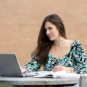 女孩在外面的桌子上用电脑学习