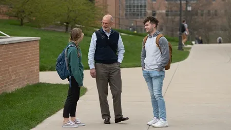 教授在外面的人行道上与一男一女学生交谈