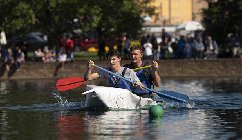Students racing across Cedar Lake in a cardboard canoe