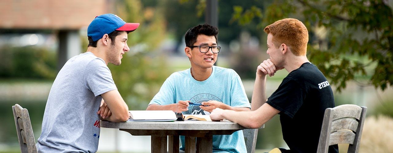 三个男学生在露台的桌子上做作业