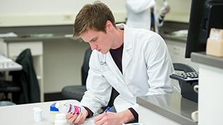 一位药学专业的男学生在读瓶子上的标签