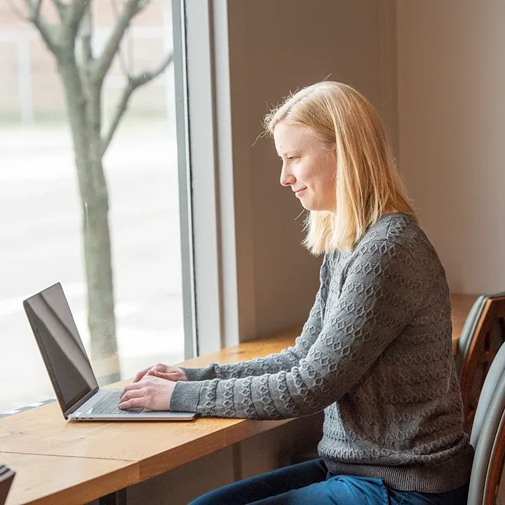 Woman sitting at desk by a window working on a laptop